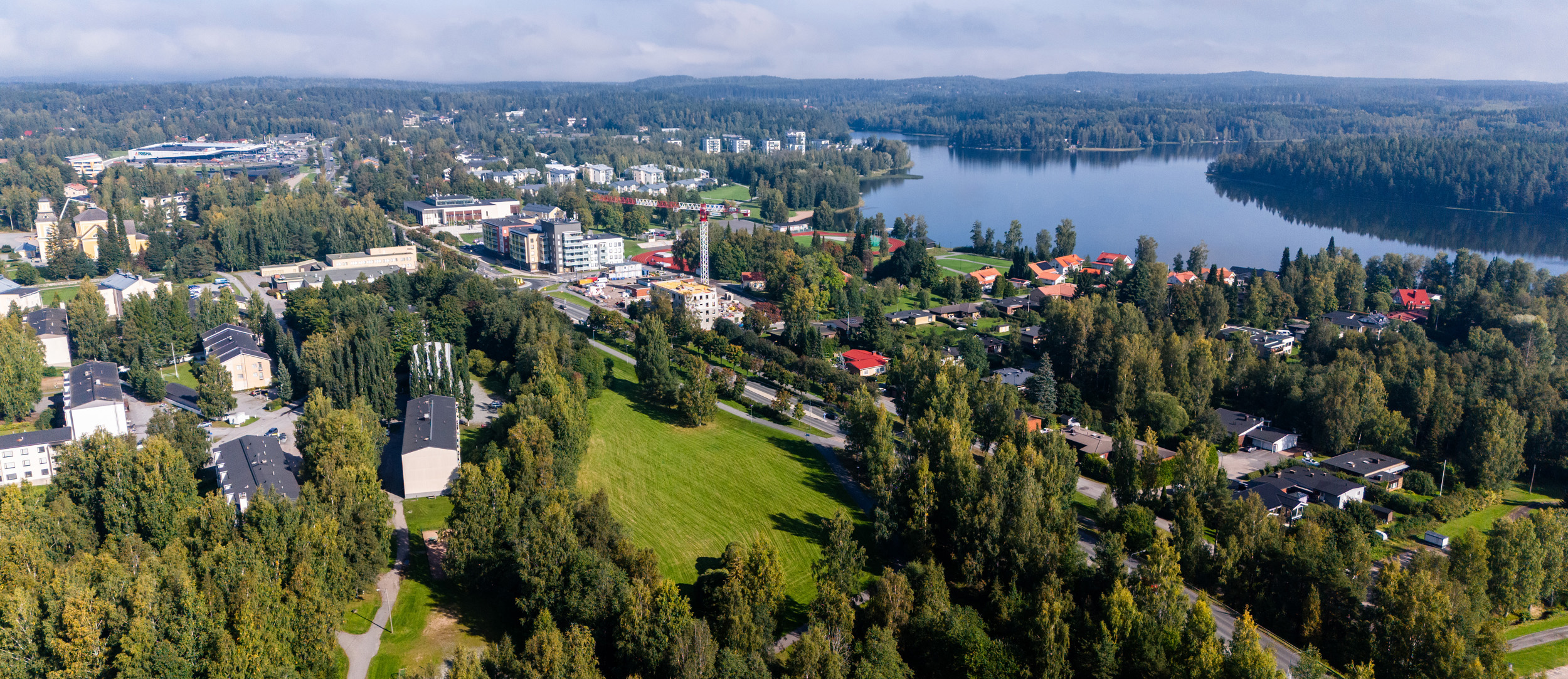 Ilmakuva taajamasta: teitä, rakennuksia, metsää ja järvi.