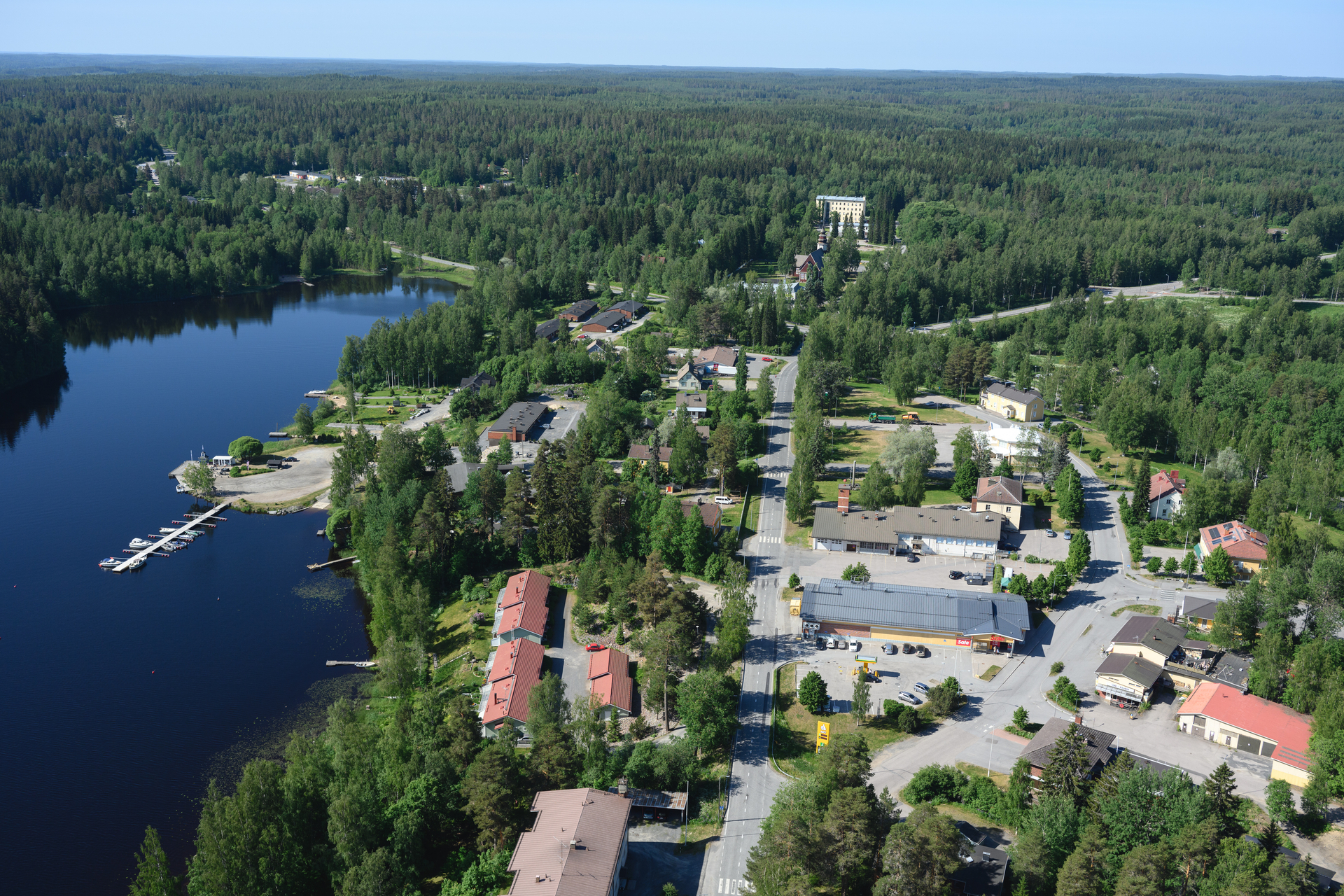 Ilmakuva taajama-alueesta. Järvi, metsää ja taloja.