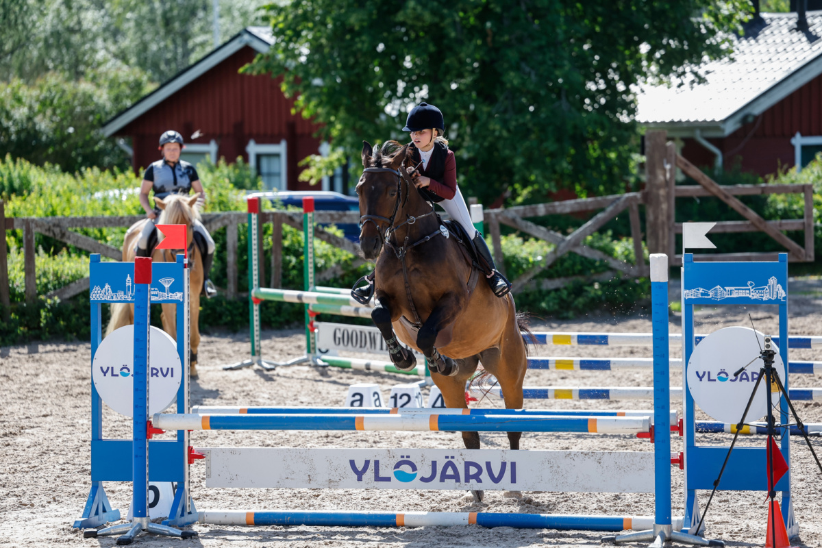 Hevonen ja ratsastaja hyppäävät esteen yli.